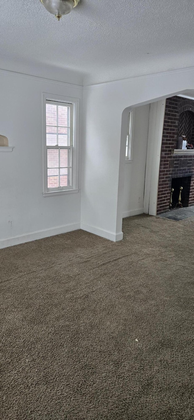 unfurnished living room with carpet floors, a textured ceiling, and a fireplace