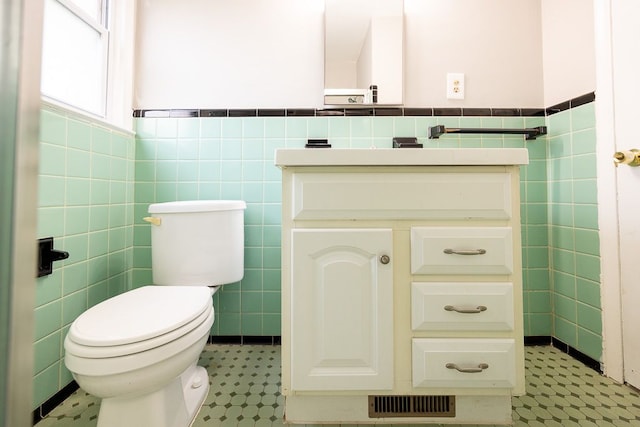 bathroom featuring vanity, toilet, and tile walls