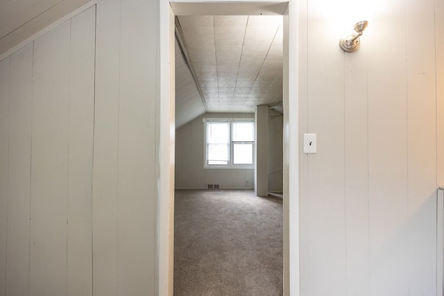 bonus room featuring vaulted ceiling, carpet flooring, and wooden walls