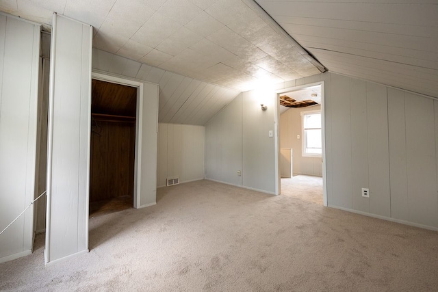 additional living space featuring lofted ceiling and light carpet