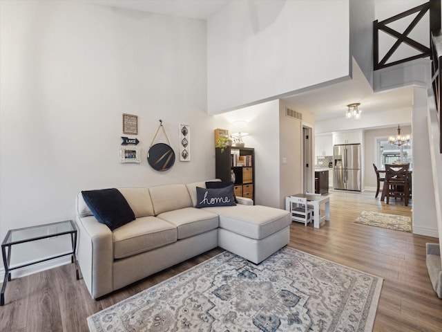 living room featuring hardwood / wood-style floors, a notable chandelier, and a high ceiling