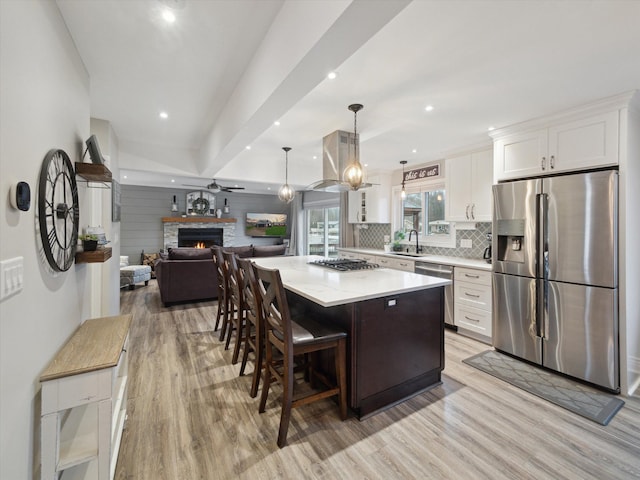 kitchen featuring sink, white cabinetry, decorative light fixtures, a center island, and appliances with stainless steel finishes