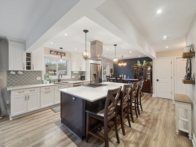 kitchen featuring sink, a kitchen island, stainless steel appliances, island exhaust hood, and decorative light fixtures