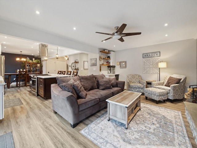 living room featuring ceiling fan with notable chandelier and light hardwood / wood-style floors