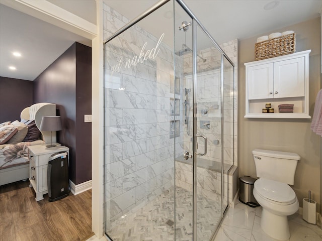 bathroom featuring wood-type flooring, a shower with door, and toilet