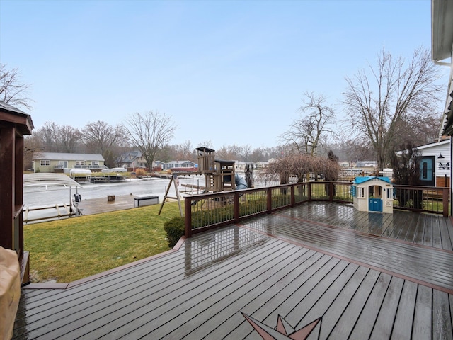 wooden deck featuring a lawn, a playground, and a water view