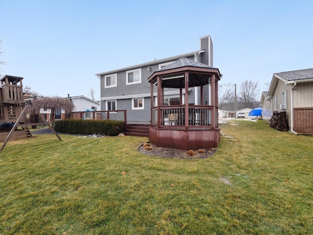 back of property with a gazebo, a deck, and a lawn