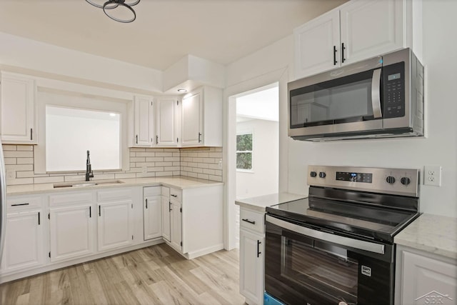 kitchen featuring stainless steel appliances, sink, white cabinets, and backsplash