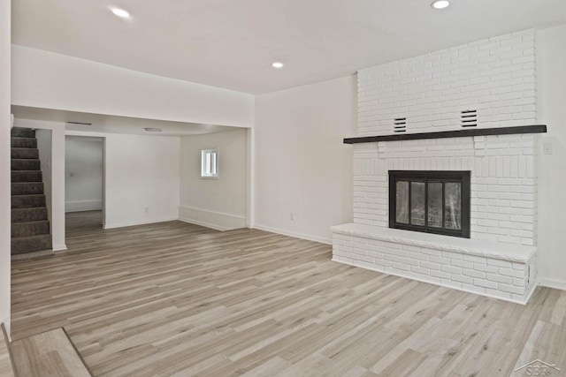 unfurnished living room with a brick fireplace and light wood-type flooring