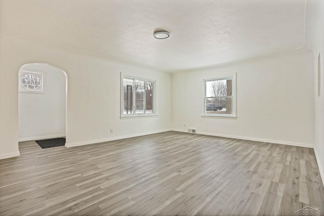 spare room with light hardwood / wood-style floors and a textured ceiling