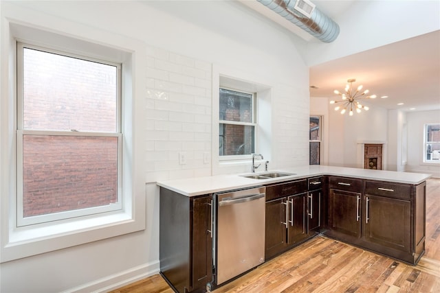 kitchen featuring sink, dark brown cabinets, light wood-type flooring, stainless steel dishwasher, and kitchen peninsula