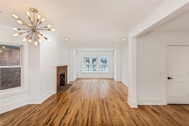 unfurnished living room featuring hardwood / wood-style flooring, a notable chandelier, and a fireplace