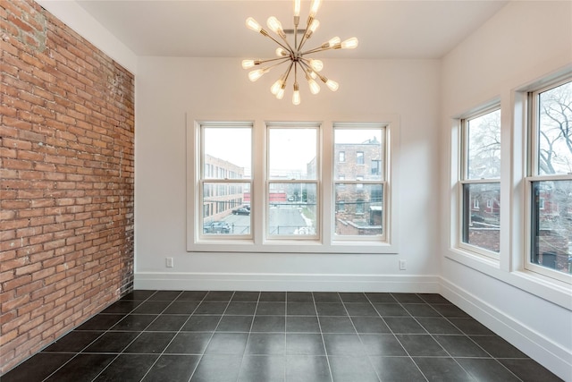 tiled spare room featuring brick wall and a chandelier