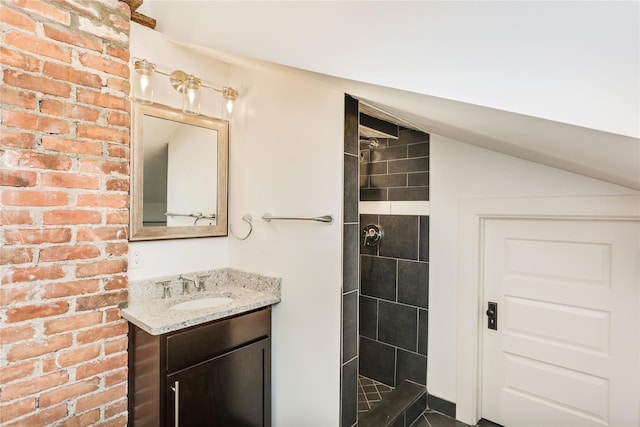 bathroom with vanity, lofted ceiling, and a tile shower