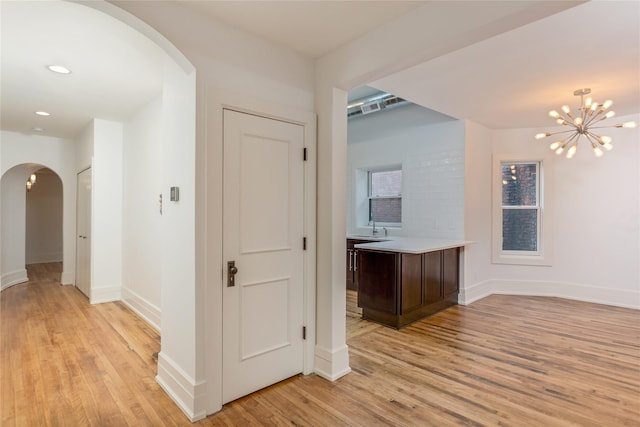 hall featuring sink, an inviting chandelier, and light hardwood / wood-style flooring