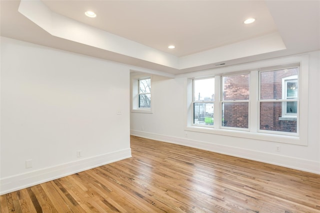 unfurnished room featuring a tray ceiling and light hardwood / wood-style flooring