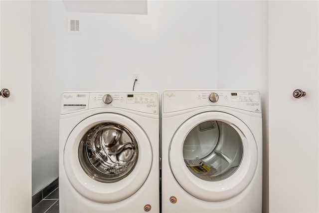 washroom with independent washer and dryer and dark tile patterned flooring