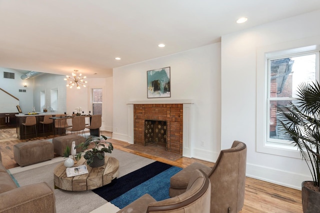 449 W Willis St Unit 4, Detroit, MI 48201 - living area featuring light wood finished floors, an inviting chandelier, visible vents, baseboards, and a brick fireplace