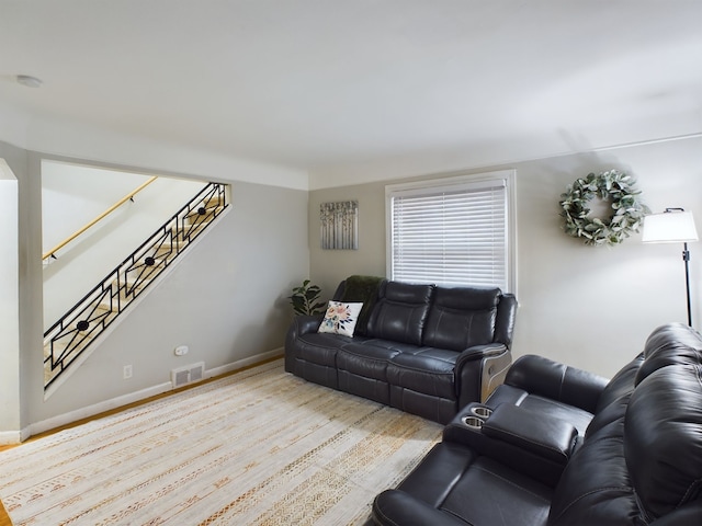 living area featuring visible vents, baseboards, wood finished floors, and stairway