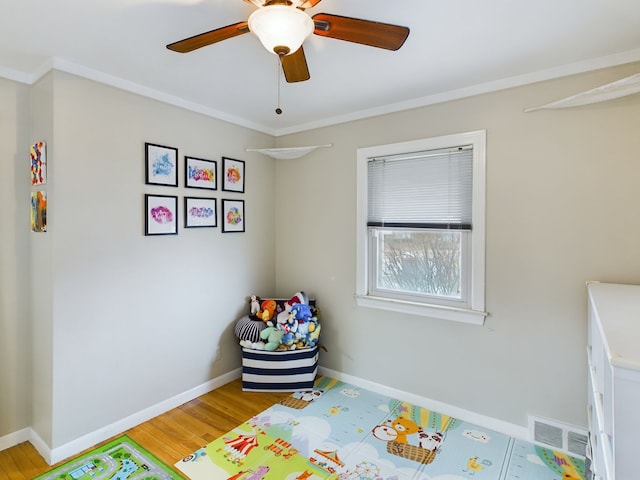 recreation room featuring visible vents, baseboards, light wood-style floors, and crown molding