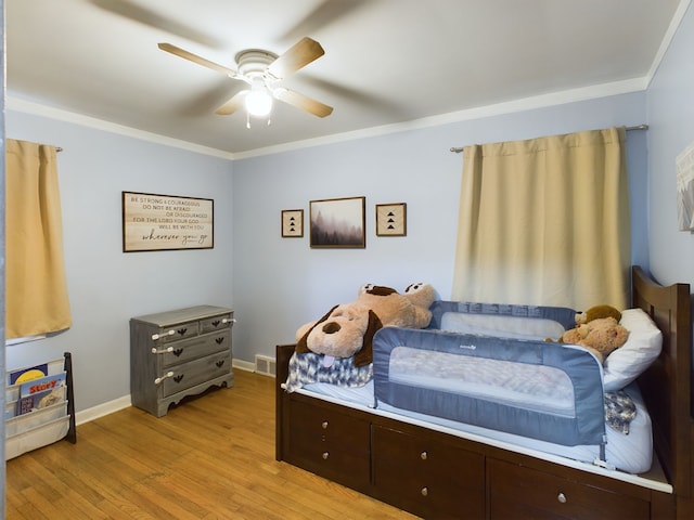 bedroom with light wood-type flooring, visible vents, a ceiling fan, crown molding, and baseboards