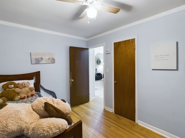 bedroom featuring ceiling fan, baseboards, crown molding, and light wood-style floors