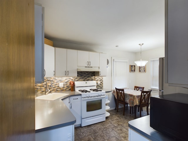 kitchen featuring white range with gas stovetop, a sink, white cabinets, under cabinet range hood, and tasteful backsplash