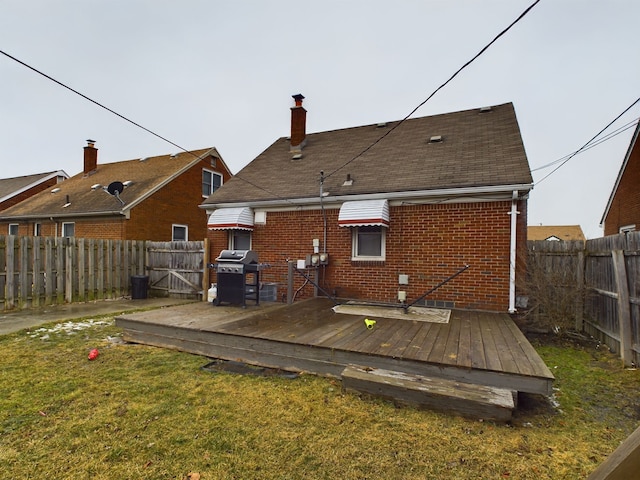 back of house with a deck, brick siding, a fenced backyard, and a lawn