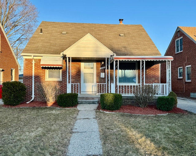 view of front of property with a front lawn, brick siding, and covered porch