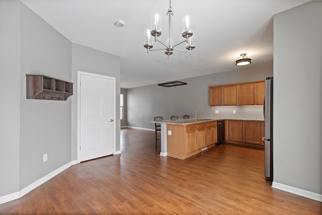 kitchen featuring stainless steel refrigerator, kitchen peninsula, pendant lighting, light hardwood / wood-style floors, and decorative backsplash