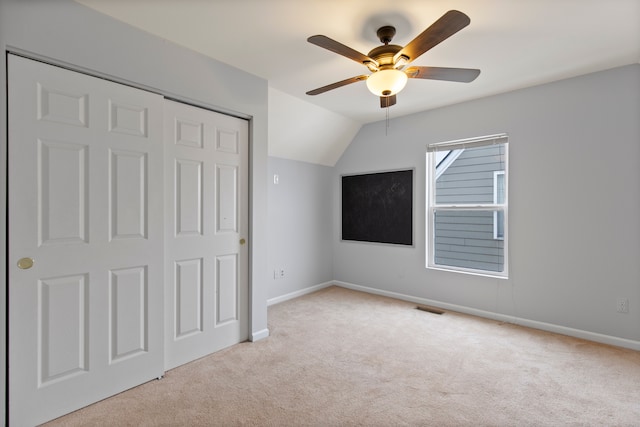 unfurnished bedroom featuring lofted ceiling, light colored carpet, a closet, and ceiling fan