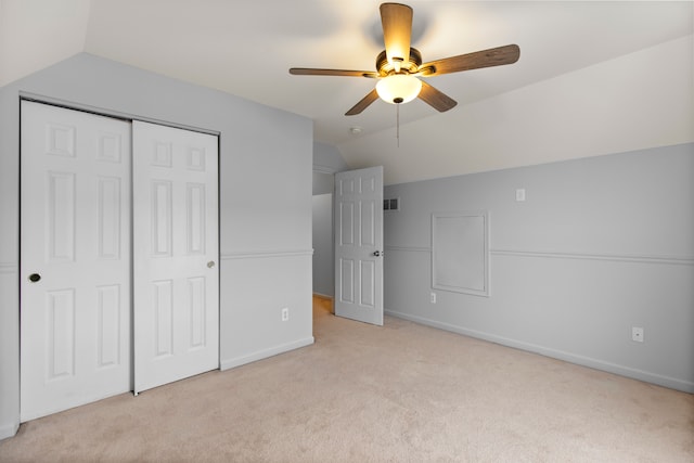 unfurnished bedroom featuring ceiling fan, light colored carpet, lofted ceiling, and a closet