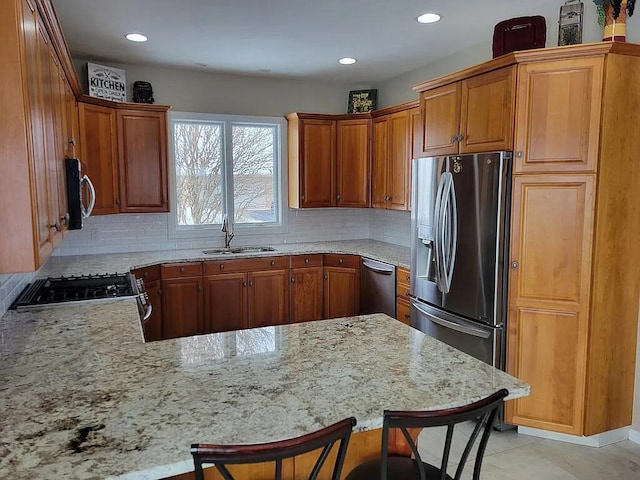 kitchen featuring sink, a breakfast bar area, kitchen peninsula, stainless steel appliances, and decorative backsplash