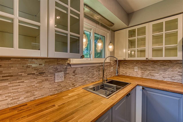 kitchen with wooden counters, sink, pendant lighting, and backsplash