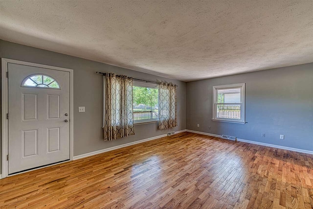 foyer featuring plenty of natural light, light hardwood / wood-style flooring, and a textured ceiling