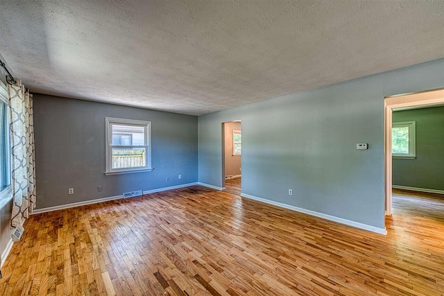 unfurnished room with a textured ceiling and light wood-type flooring