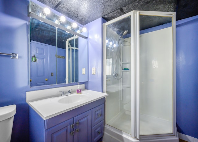 bathroom with vanity, toilet, a shower with door, and a textured ceiling