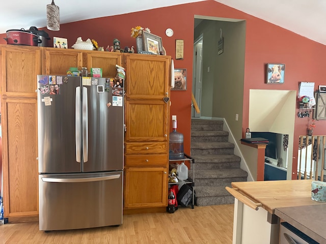 kitchen featuring stainless steel fridge, light hardwood / wood-style floors, and vaulted ceiling