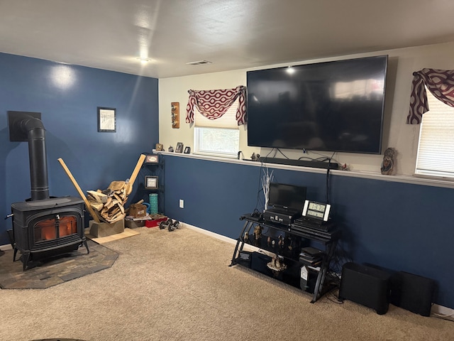 recreation room featuring carpet flooring and a wood stove