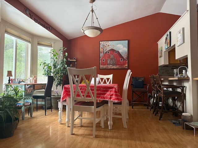 dining space featuring lofted ceiling and light hardwood / wood-style flooring