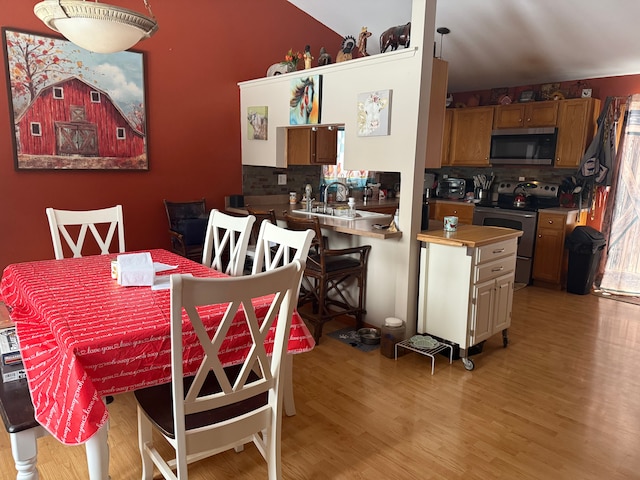 kitchen with backsplash, sink, stainless steel appliances, and light hardwood / wood-style floors