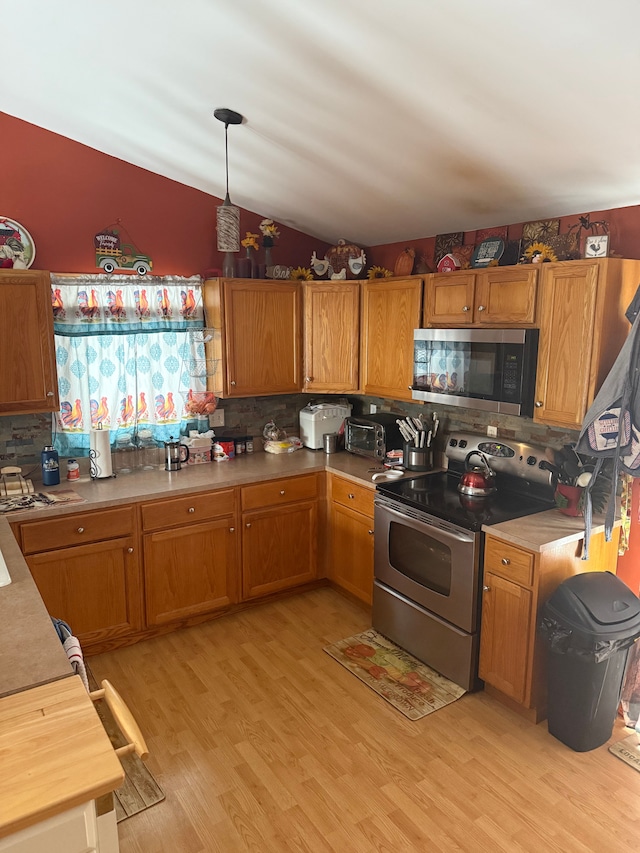 kitchen with tasteful backsplash, decorative light fixtures, vaulted ceiling, light hardwood / wood-style flooring, and stainless steel appliances