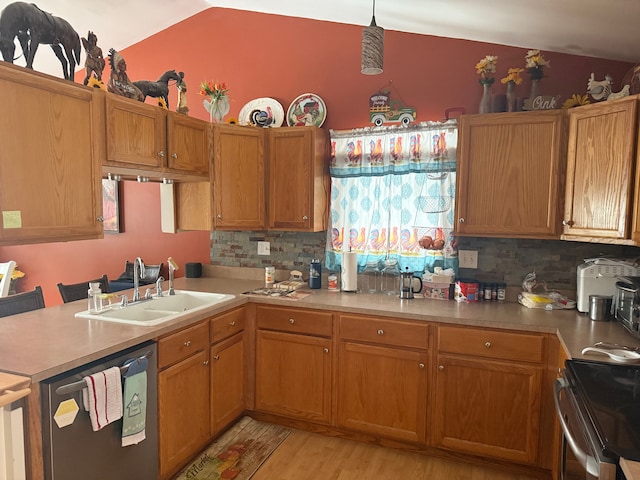 kitchen with pendant lighting, lofted ceiling, sink, light hardwood / wood-style floors, and stainless steel appliances