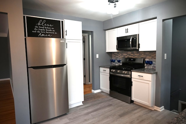 kitchen featuring white cabinetry, stainless steel appliances, decorative backsplash, and dark stone counters