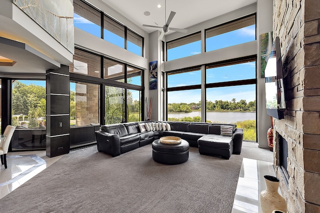 carpeted living room with a high ceiling, a water view, a healthy amount of sunlight, and a fireplace