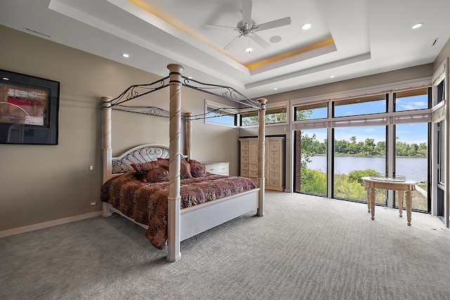 carpeted bedroom with a tray ceiling, a high ceiling, and a water view