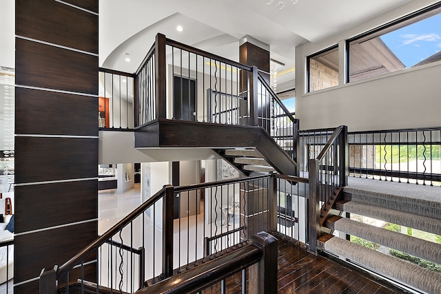 staircase with a towering ceiling and wood-type flooring