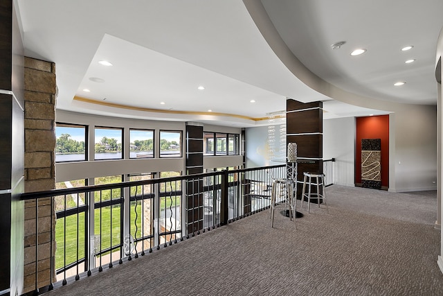 hallway featuring a tray ceiling and carpet flooring