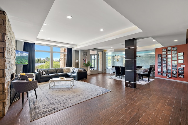 living room featuring dark hardwood / wood-style floors, a fireplace, and a tray ceiling