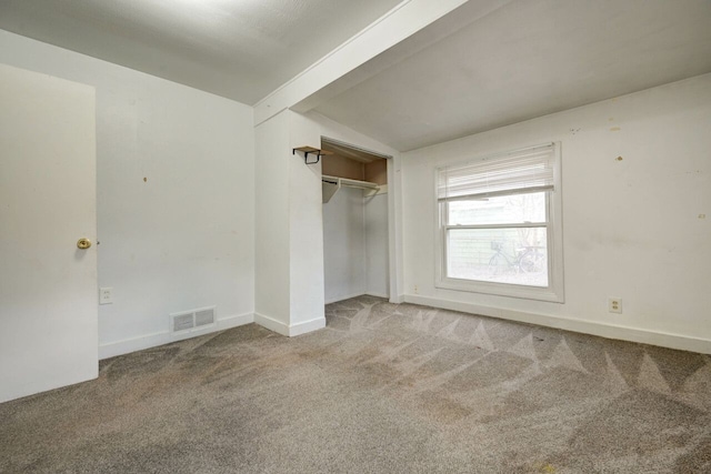 unfurnished bedroom with a closet, lofted ceiling with beams, and light carpet